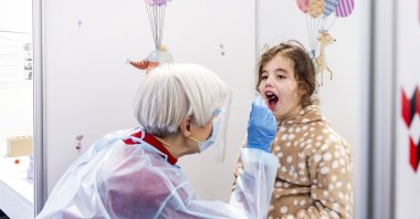 A health worker collects a throat swab sample from a child to test for COVID-19 at a special children's testing center in Amsterdam, the Netherlands, March 26, 2021. (AFP Photo)