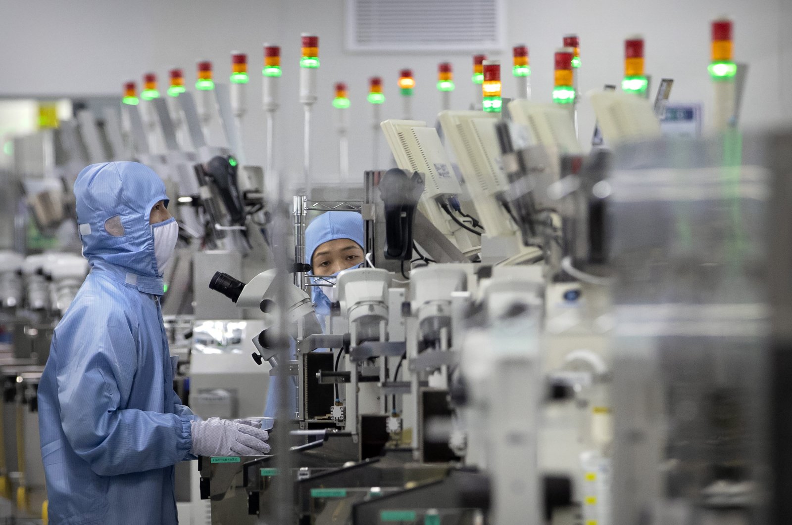 Employees wearing protective equipment work at a semiconductor production facility for Renesas Electronics seen during a government-organized tour for journalists, Beijing, China, May 14, 2020. (AP Photo)