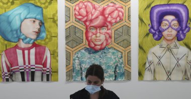 A gallery employee works in front of Angeles Agrela paintings at the 14th edition of Art Dubai at Dubai International Financial Centre, Dubai, United Arab Emirates, March 30, 2021. (AP Photo)