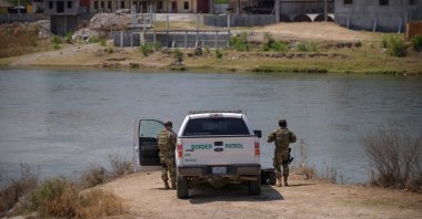 U.S. border patrol agents stand before the Rio Grande river and a suburb of the Mexican city of Ciudad Miguel Aleman, in the southern Texas border city of Roma, U.S., March 27, 2021. (AFP Photo)