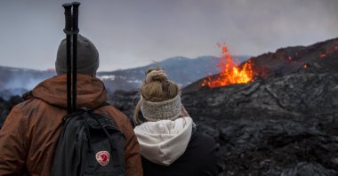 People watch the Lava flows from an eruption of a volcano on the Reykjanes Peninsula in southwestern Iceland on Wednesday, March 31, 2021. (AP Photo)