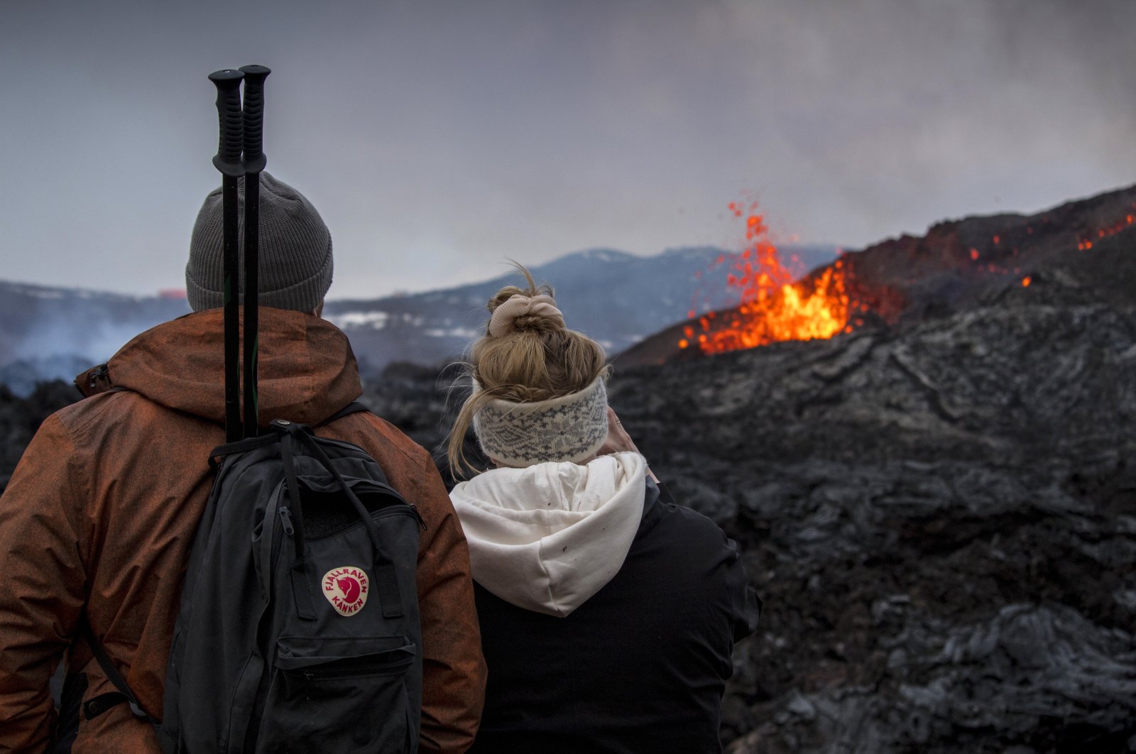 People watch the Lava flows from an eruption of a volcano on the Reykjanes Peninsula in southwestern Iceland on Wednesday, March 31, 2021. (AP Photo)