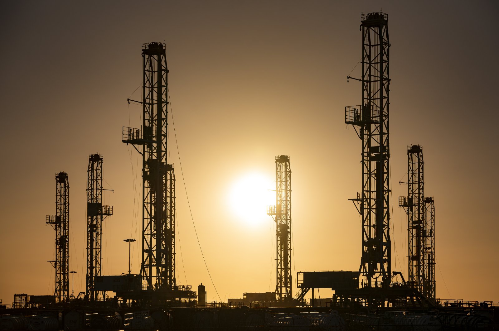 The morning sun rises behind oil rigs sitting in storage at a yard outside of Odessa, Texas, U.S., Feb. 6, 2021. (Odessa American via AP)