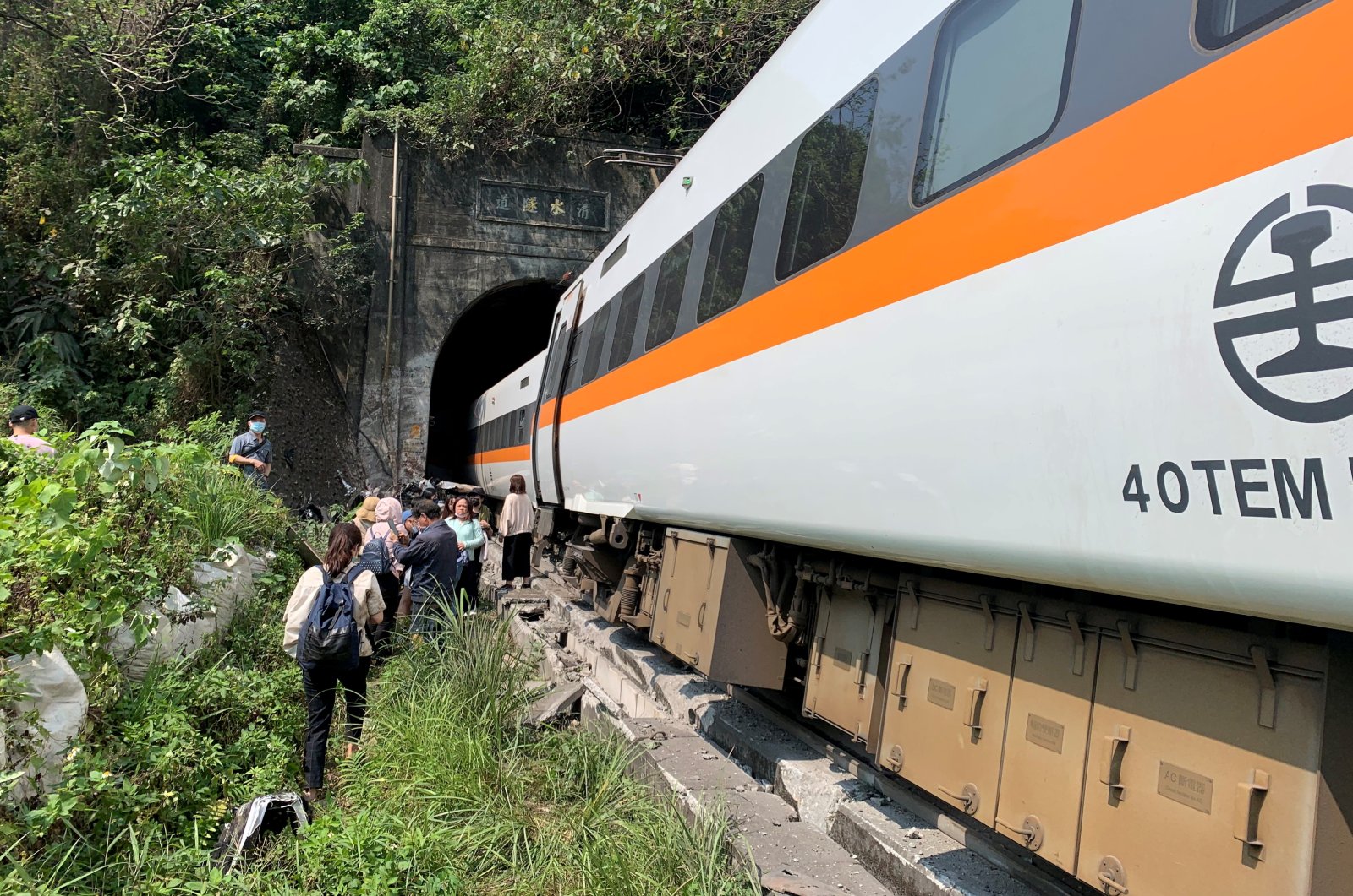 People walk next to a train which derailed in a tunnel north of Hualien, Taiwan, April 2, 2021, (Taiwan's National Fire Agency via Reuters)