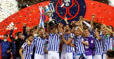 A handout photo made available by the Spanish Royal Soccer Federation (RFEF) shows Real Sociedad players after receiving the trophy from Spain's King Felipe VI (CL) after winning the 2020 Copa Del Rey final match against Athletic Bilbao at La Cartuja stadium in Seville, Andalusia, Spain, April 03, 2921. (RFEF via EPA)