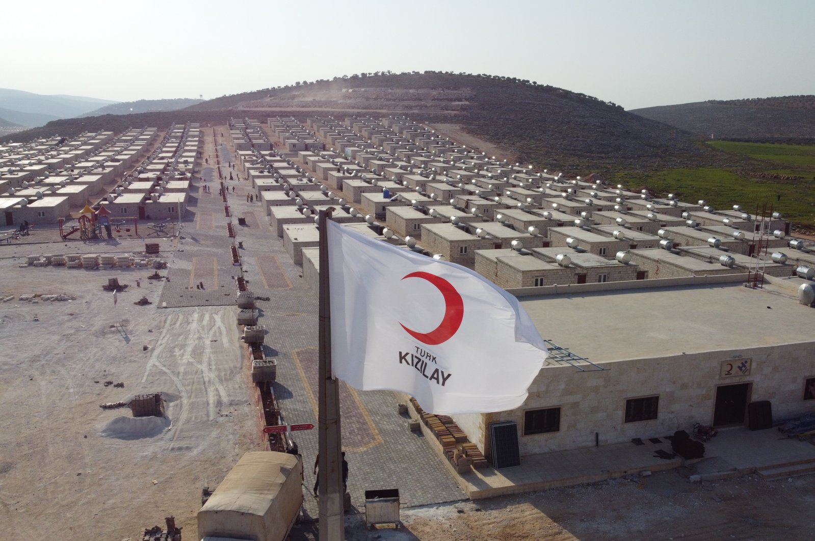 A Turkish Red Crescent (Kızılay) flag waves over houses built by Kızılay for displaced Syrians in Sarmada, Idlib province, Syria, April 3, 2021. (AA Photo) 