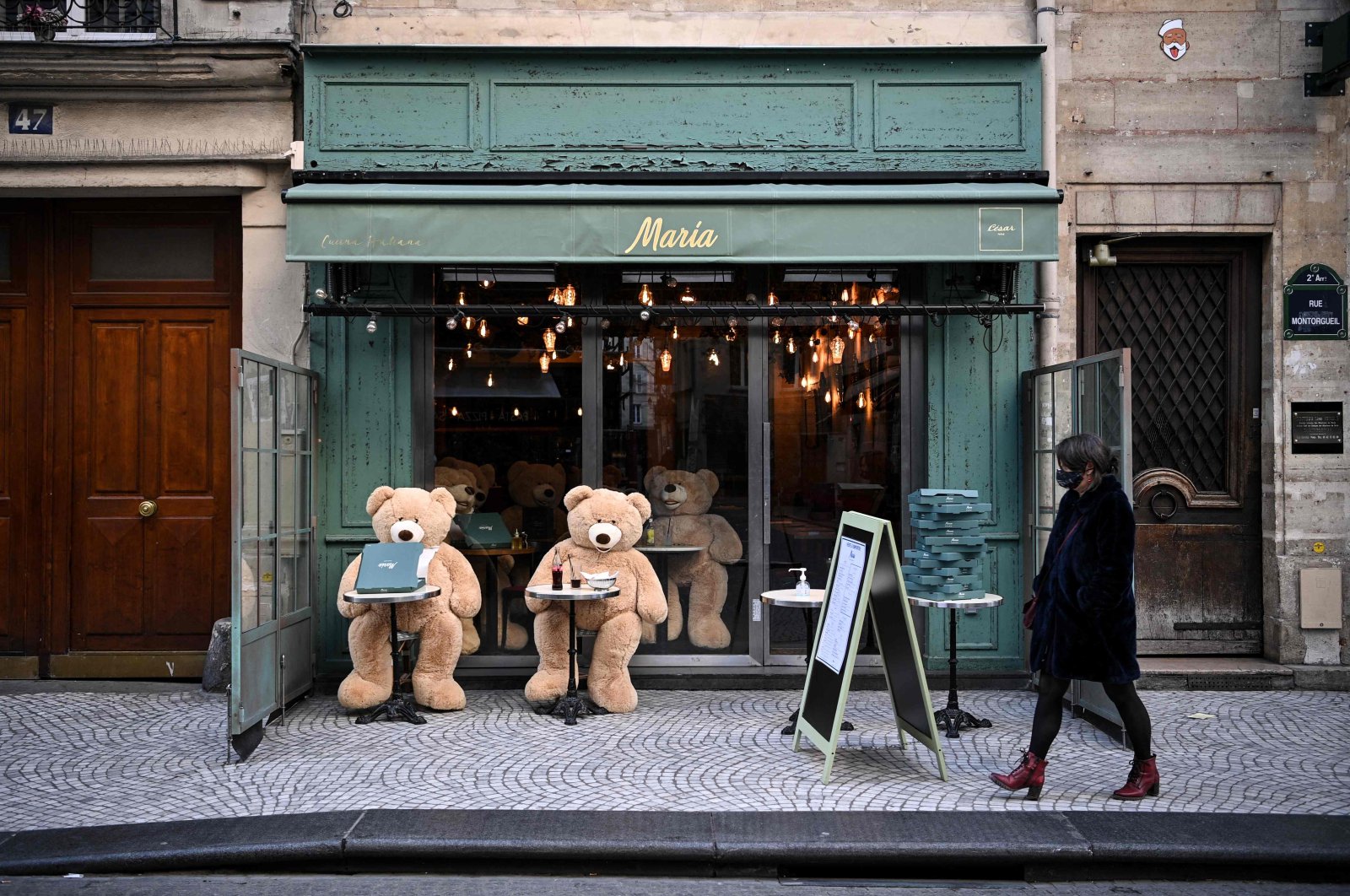 A woman walks in front of teddy bears displayed on the terrace of a closed restaurant in Paris, France, March 20, 2021. (AFP Photo)