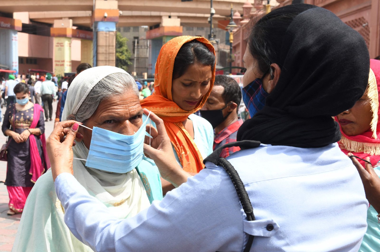 A private security guard ties a mask over the face of a woman during an awareness campaign against the spread of the COVID-19 coronavirus, Amritsar, India, April 4, 2021. (AFP Photo)