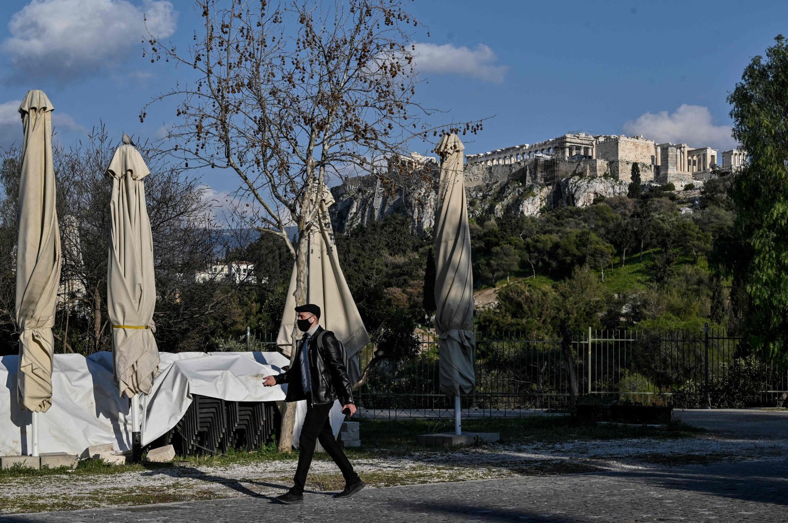 A man walks past a closed cafe with the Acropolis in the background in Athens, Greece, April 1, 2021. (AFP Photo)