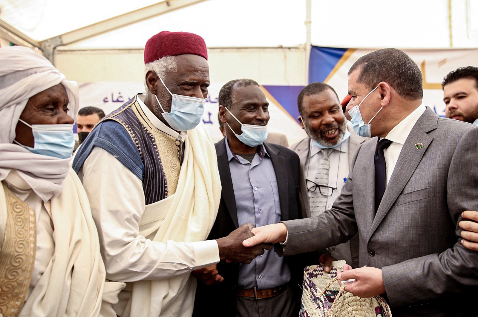 Libyan Prime Minister Abdul Hamid Dbeibah (R) shakes hands with elders at a rally during his visit to Tawergha, some 200 kilometers (125 miles) east of Libya's capital close to the port city of Misrata, April 3, 2021. (AFP Photo)