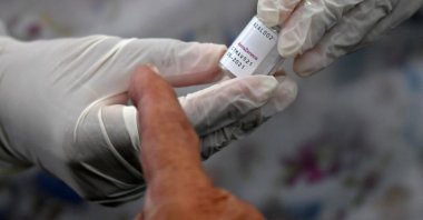 A health worker prepares an Oxford/AstraZeneca vaccine against COVID-19 as people wait amid the coronavirus pandemic, Bogota, Colombia April 7, 2021. (Photo by Raul ARBOLEDA / AFP)