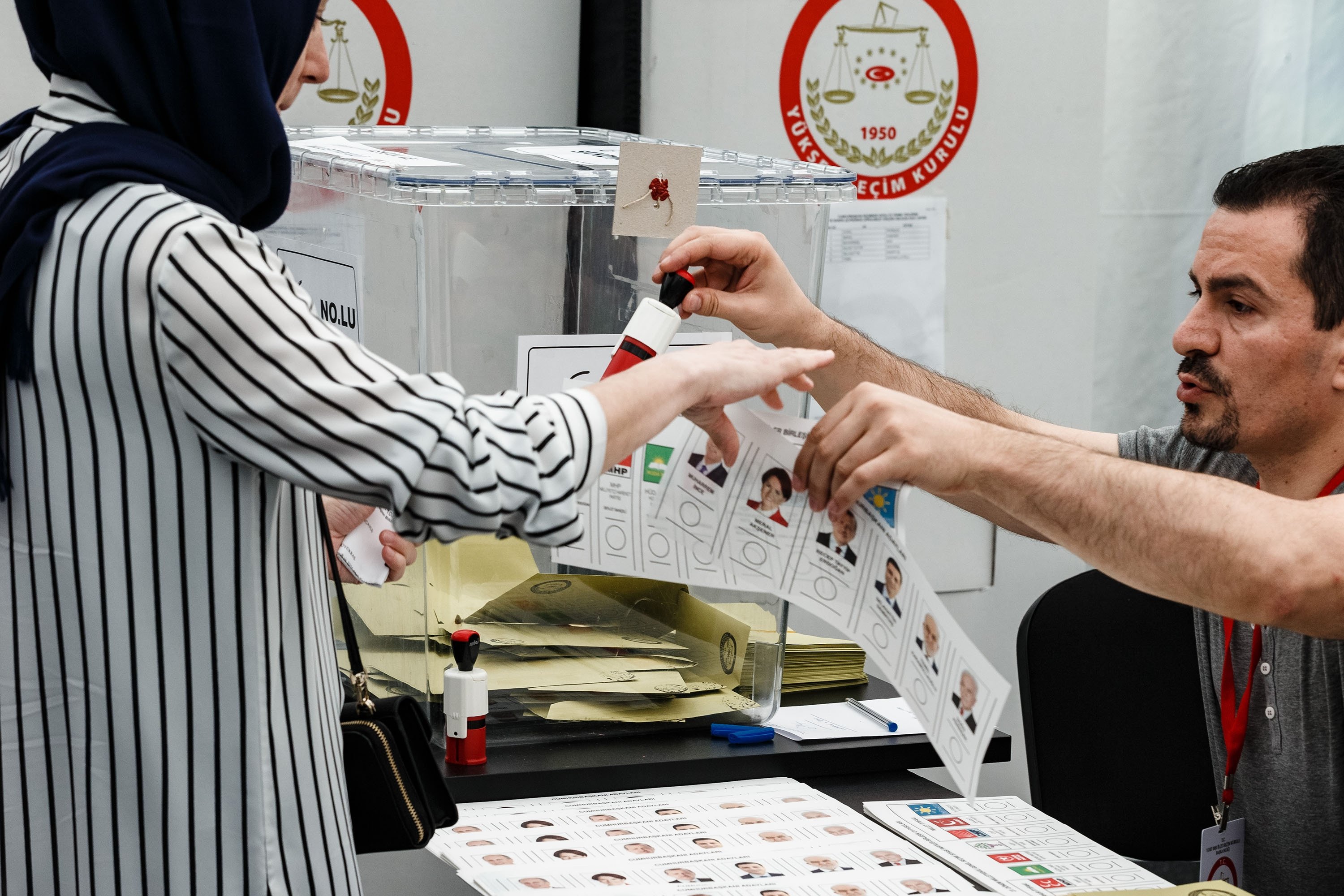 A member of the electoral commission gives a Turkish woman ballot paper and the stamp to mark her candidates, Hamburg, June 7, 2018. (Getty Images)
