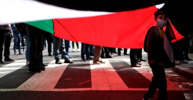 A young boy stands beneath a Palestinian flag as protesters from multiple Palestinian rights organizations demonstrate outside the White House, Washington, D.C., U.S., Sept. 15, 2020. (Photo by Getty Images)