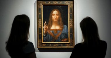 Christie's employees pose in front of a painting entitled "Salvator Mundi" at a photocall at Christie's auction house in central London, U.K., Oct. 22, 2017, ahead of its sale at Christie's New York on Nov. 15, 2017. (AFP Photo)