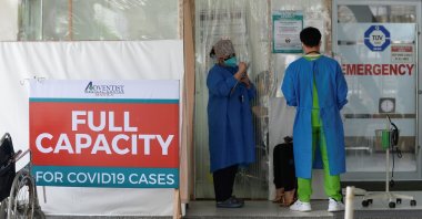 Health workers assess a patient outside the emergency room at the Adventist Medical Center, where a sign indicating that the hospital's coronavirus facility is at full capacity is displayed, in Pasay, the Philippines, April 9, 2021. (Reuters Photo)