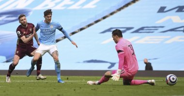 Leeds United's Stuart Dallas (L) kicks the ball past Manchester City's John Stones and goalkeeper Ederson to score his team's second goal during the English Premier League soccer match at Etihad Stadium, Manchester, England, April 10, 2021. (AP/Michael Regan/Pool Photo)