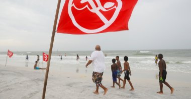 A strong current warning sign blows in the wind while beachgoers enjoy the Gulf of Mexico before a storm front approaches Clearwater Beach in Clearwater, Florida, U.S. March 18, 2021. (Reuters Photo)