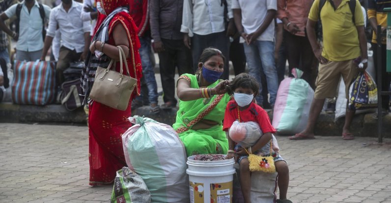 A woman adjusts the mask of her child as they wait for a train at Lokmanya Tilak Terminus in Mumbai, India, April 11, 2021. (AP Photo)