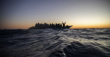 Migrants and refugees from different African nationalities wait for assistance on an overcrowded wooden boat in the Mediterranean Sea, international waters, at 122 miles (196 kilometers) off the Libyan coast, Feb. 12, 2021. (AP Photo)