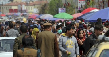 A man wearing a protective face mask to help curb the spread of the coronavirus walks among crowds in a street market in Kabul, Afghanistan, April 7, 2021. (AP Photo)