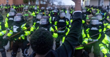 A man raises his fist as he faces the Minnesota State Troopers standing guard outside the Brooklyn Center Police Station after a police officer shot and killed 20-year-old Daunte Wright during a traffic stop in Brooklyn Center, Minneapolis, Minnesota, April 12, 2021. (AFP Photo)
