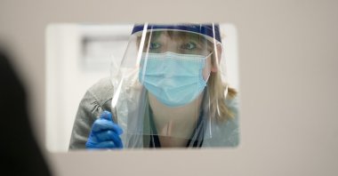A pupil is assisted during a Lateral Flow Test at a school in in Manchester, England, March 8, 2021. (PA via AP)