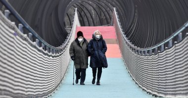 People wear protective face masks as they walk over a bridge during the lockdown in Oberhausen, Germany, on Monday, Jan. 11, 2021. (AP Photo)