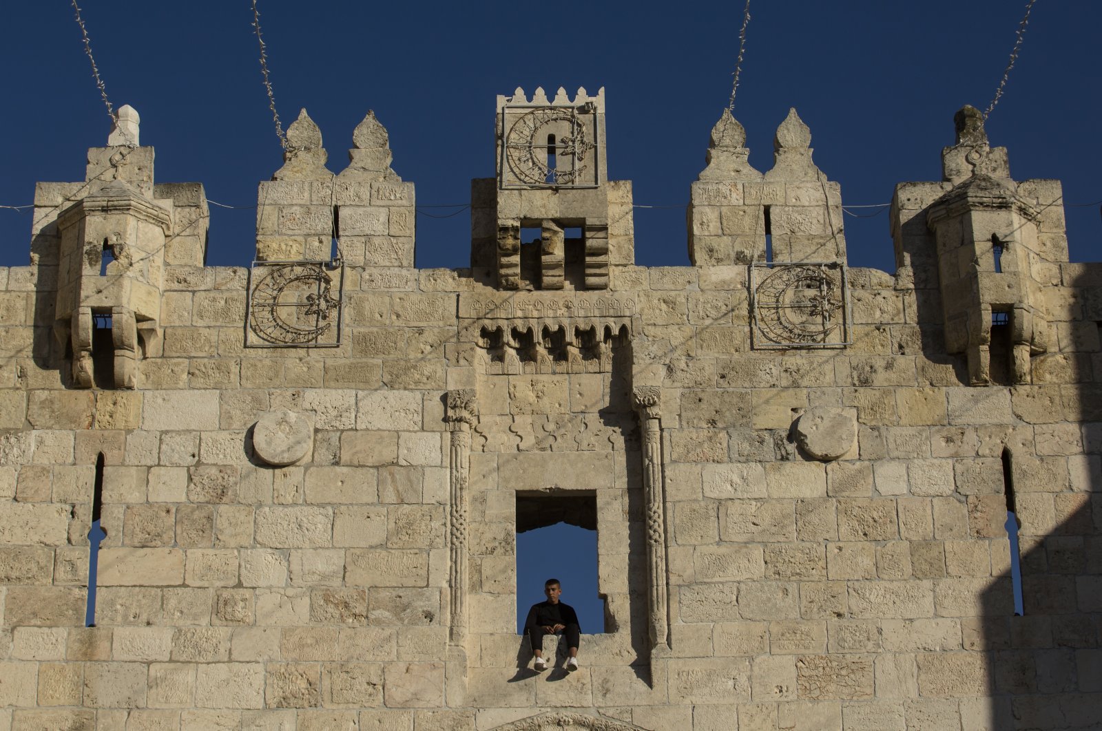 A Muslim man sits on Damascus Gate ahead of the first evening of the holy Muslim month of Ramadan, Old City, Israeli-occupied East Jerusalem, April 12, 2021. (Photo by Getty Images)