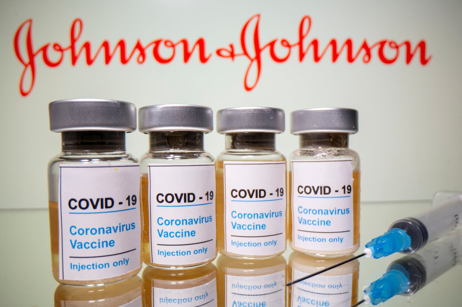 Vials with a sticker reading, "COVID-19 / Coronavirus vaccine / Injection only" and a medical syringe are seen in front of the Johnson & Johnson logo in this illustration, Oct. 31, 2020. (Reuters Photo)