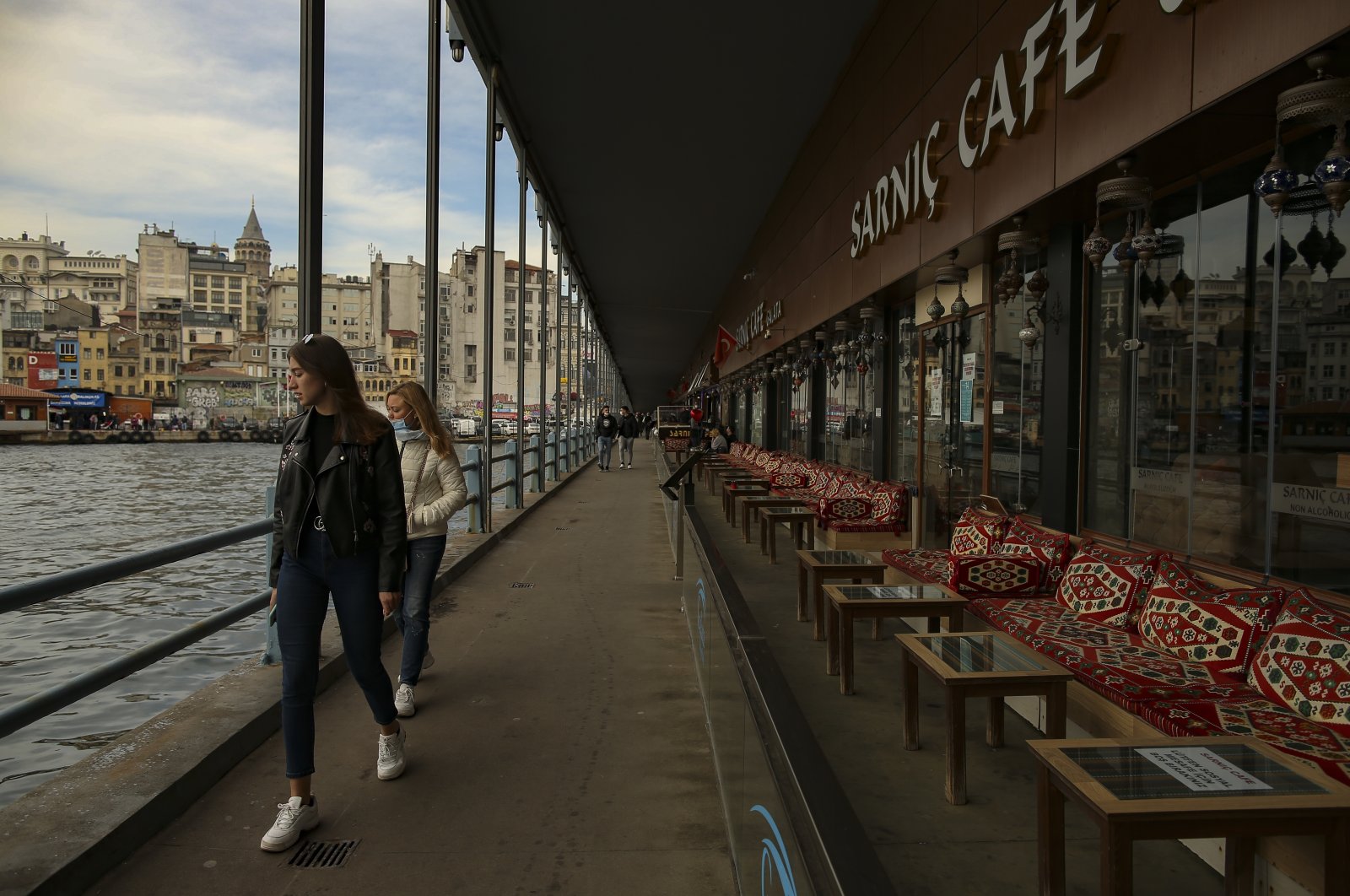 People walk past a cafe over Galata Bridge, in Istanbul, Turkey, April 13, 2021. (AP Photo)