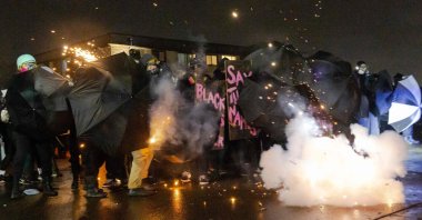 Demonstrators protect themselves with umbrellas against tear gas and pepper balls outside the Brooklyn Center police station as they protest the death of Daunte Wright who was shot and killed by a police officer, in Brooklyn Center, Minnesota, the U.S., April 13, 2021. (AFP Photo)