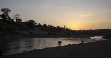 People sit on the banks of the Tekeze River, on the Sudan-Ethiopia border in Hamdayet, eastern Sudan, March 16, 2021. (AP Photo)