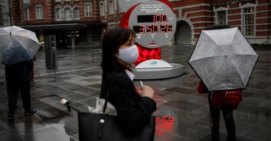 A woman wearing a protective face mask walks in front of a countdown clock showing that 100 days are left until the Tokyo 2020 Olympic Games that have been postponed to 2021 due to the COVID-19 pandemic, Tokyo, Japan, April 14, 2021. (Reuters Photo)