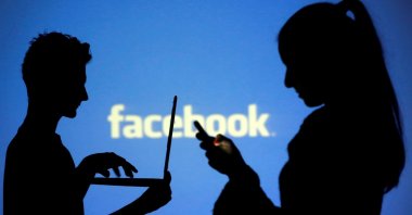 Silhouetted people pose with laptops in front of a screen projected with a Facebook logo, in this picture illustration taken in Zenica, Bosnia-Herzegovina, Oct. 29, 2014. (Reuters Photo)