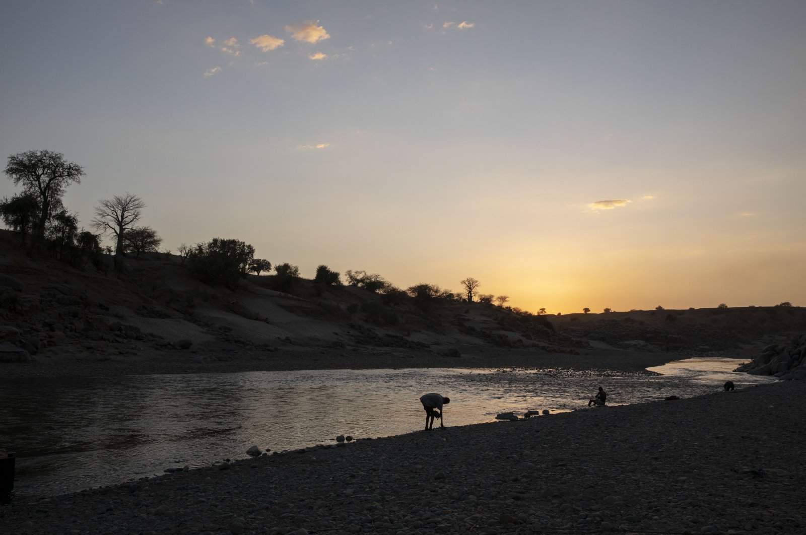 People sit on the banks of the Tekeze River, on the Sudan-Ethiopia border in Hamdayet, eastern Sudan, March 16, 2021. (AP Photo)