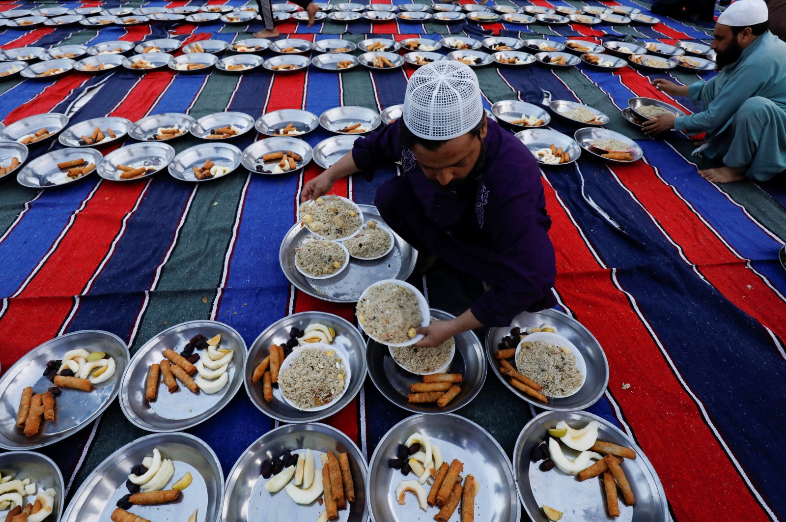 A man arranges plates of food for iftar during the fasting month of Ramadan, as the COVID-19 outbreak continues, at a mosque in Karachi, Pakistan, April 14, 2021. (Reuters Photo)