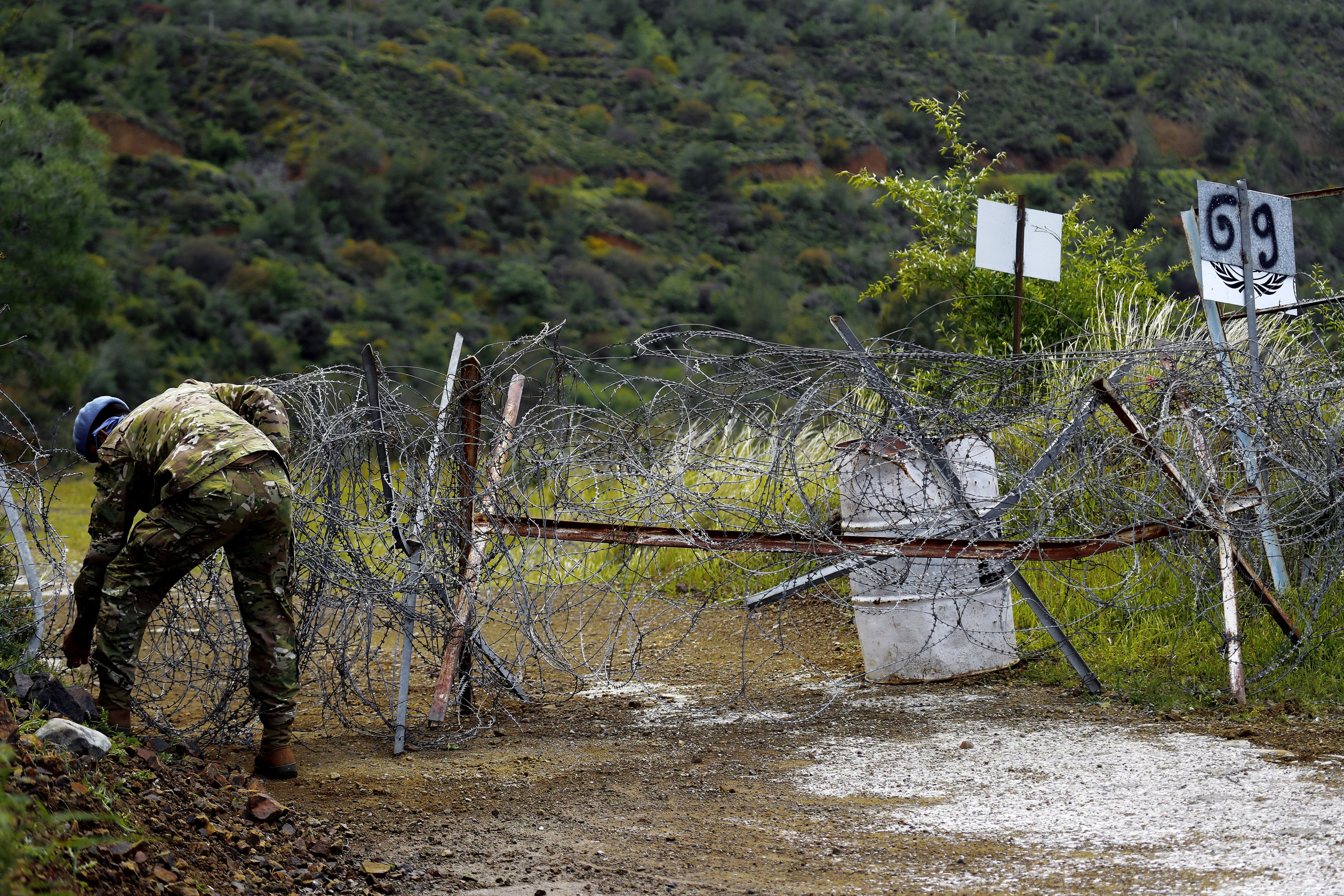 A U.N. peacekeeper removes the barbed wire from around the abandoned village of Varisia, inside the U.N.-controlled buffer zone that divides the Greek-controlled south and the Turkish-controlled north, on the island of Cyprus, March 26, 2021. (AP Photo)