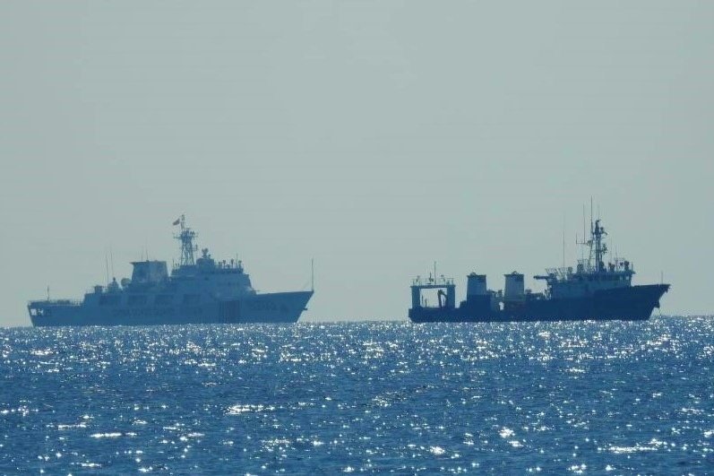 A Chinese coast guard patrol ship (L) is seen near an unidentified vessel in the South China Sea, in a handout photo distributed by the Philippine Coast Guard on April 15, 2021, and taken according to the source either on April 13 or 14, 2021. (Reuters Photo)