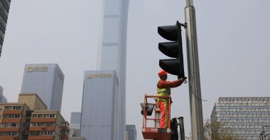 A worker installs new traffic lights at a junction in Beijing on Thursday, April 15, 2021. (AP Photo)