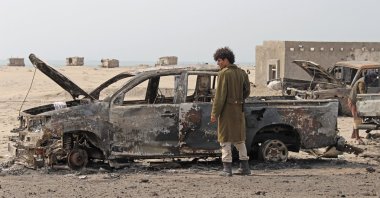 A Yemeni southern separatist fighter inspects the wreckage of government forces vehicles destroyed by UAE airstrikes near Aden, Yemen, Aug. 30, 2019. (AP Photo)