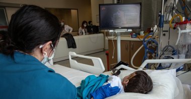 A nurse cares for a young patient watching TV at the hospital, in Istanbul, Turkey, April 16, 2021. (AA PHOTO)