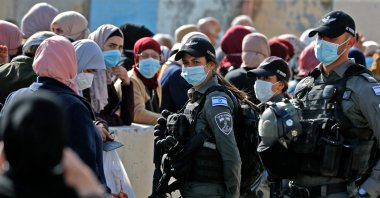 Members of the Israeli security forces man the Qalandia checkpoint near the West Bank town of Ramallah, as Palestinian women wait to enter Jerusalem to attend the first Friday prayers of the Muslim fasting month of Ramadan at the Al-Aqsa Mosque, on April 16, 2021. (AFP Photo)