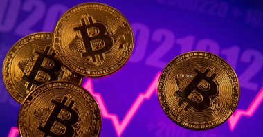 A representation of the virtual currency Bitcoin is seen in front of a stock graph in this illustration taken on March 15, 2021. (Reuters Photo)