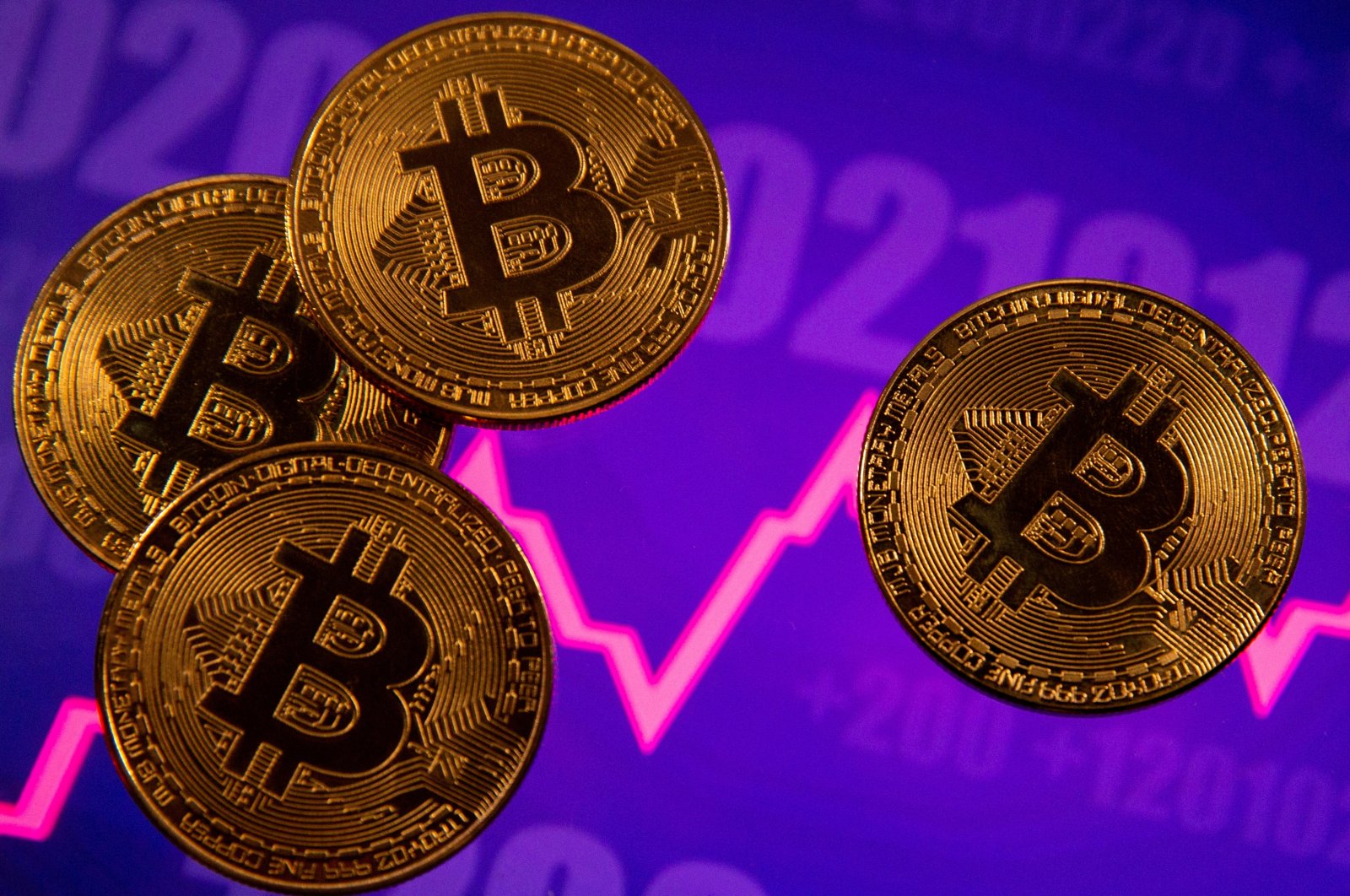 A representation of the virtual currency Bitcoin is seen in front of a stock graph in this illustration taken on March 15, 2021. (Reuters Photo)