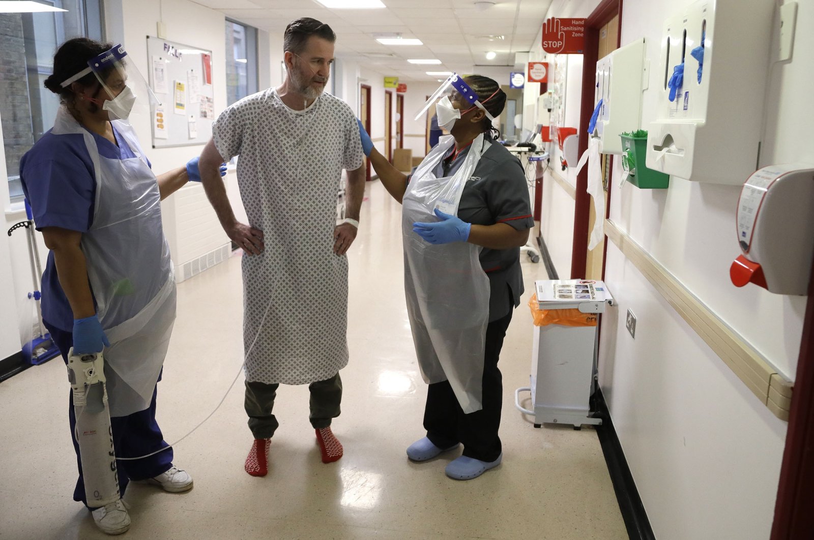 Anna Castellano (L), a senior nurse, and Felicia Kwaku (R), the associate director of nursing, help recovering COVID-19 patient Justin Fleming walk again, in the Cotton ward at King's College Hospital in London, U.K., Jan. 27, 2021. (AP Photo)