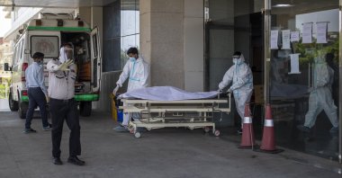 A security guard objects to taking pictures as hospital staff shift the body of a COVID-19 patient on a stretcher to a waiting ambulance at a government COVID-19 hospital in Noida, a suburb of New Delhi, India, April 21, 2021. (AP Photo)
