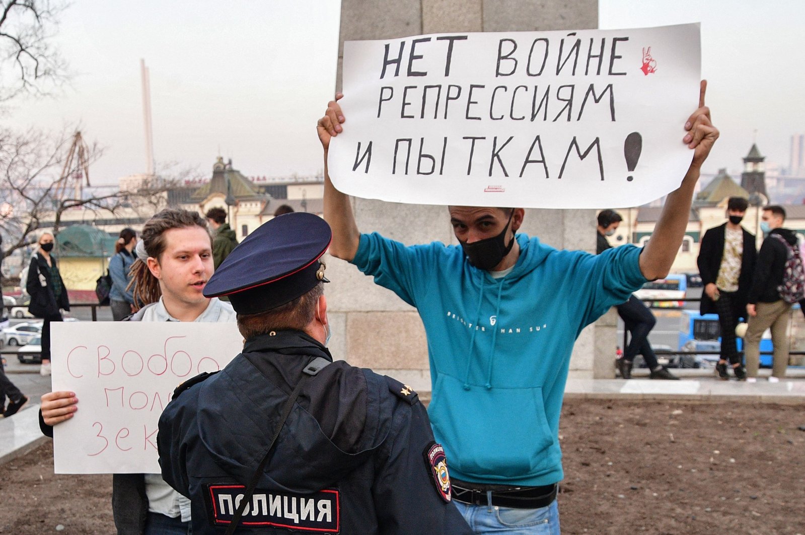 A Russian police officer speaks with an opposition supporter holding a poster reading "No war, repressions and tortures!" during a rally in support of jailed Kremlin critic Alexei Navalny in Vladivostok, Russia, April 21, 2021. (AFP Photo)