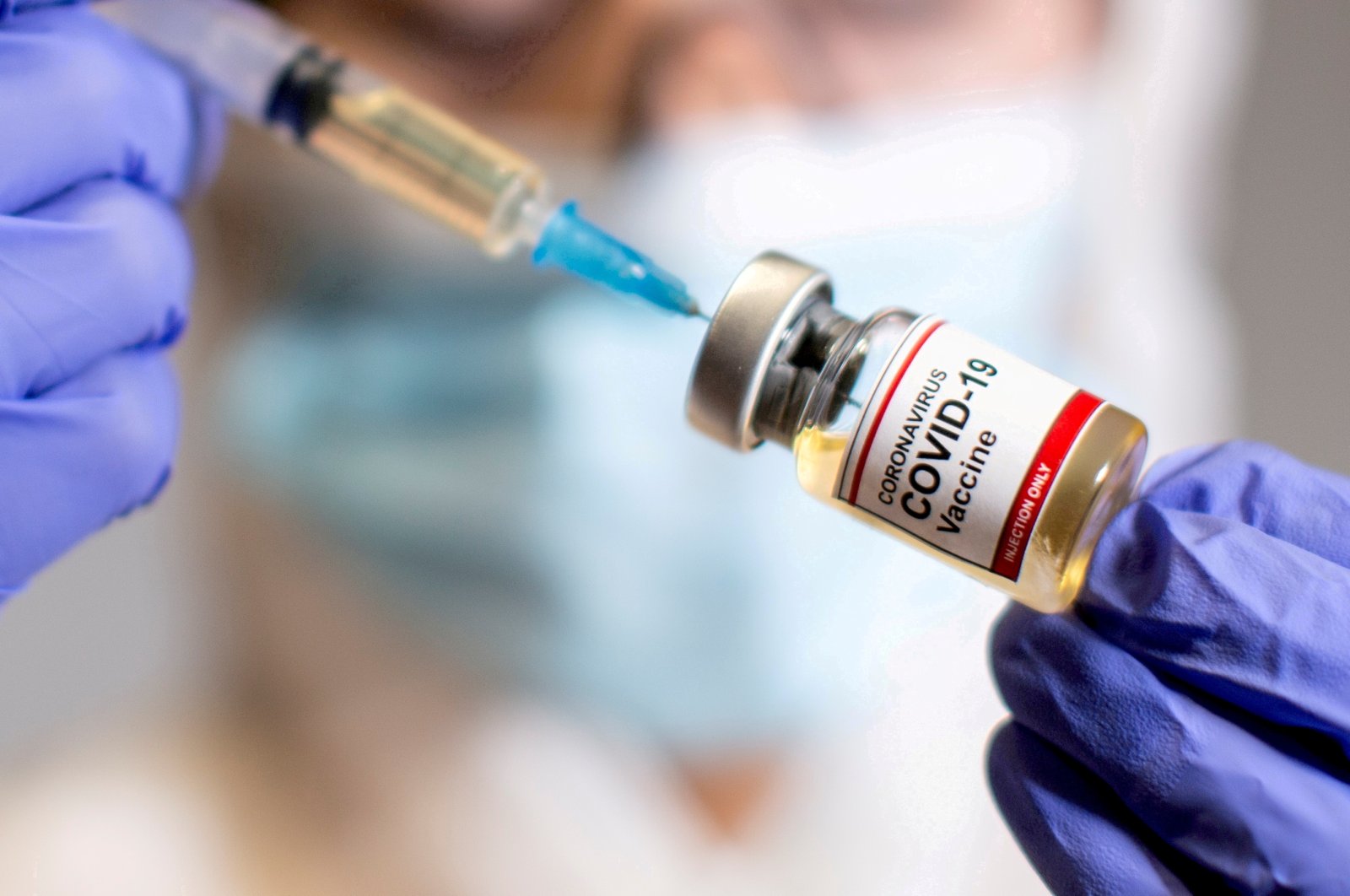 A woman holds a small bottle labelled with a "Coronavirus COVID-19 Vaccine" sticker and a medical syringe, Oct. 30, 2020. (Reuters Photo)