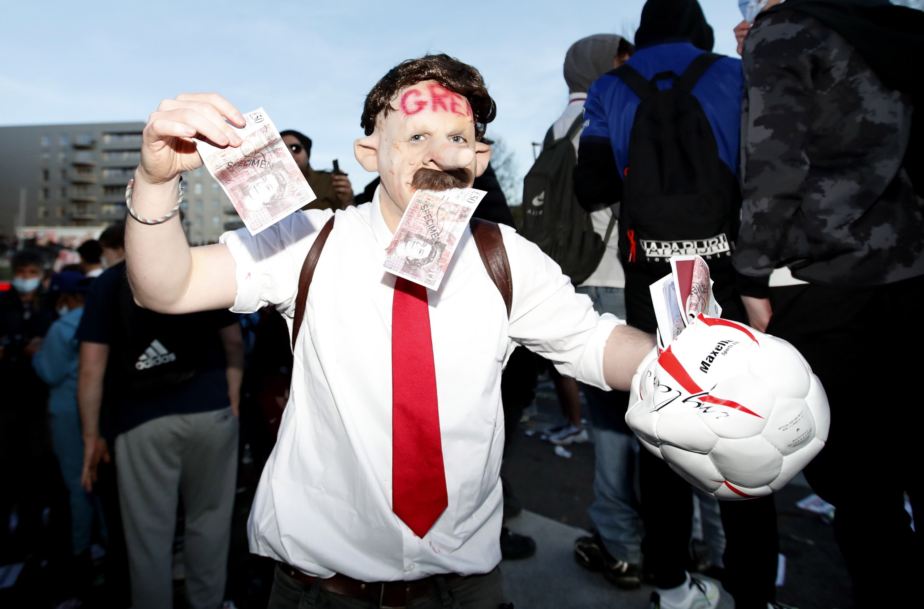 An Arsenal fan wearing a Stan Kroenke mask displays fake money during a demonstration against Arsenal's U.S. owner's involvement in the failed launch of a European Super League, Emirates Stadium, London, Britain, April 23, 2021. (Reuters)