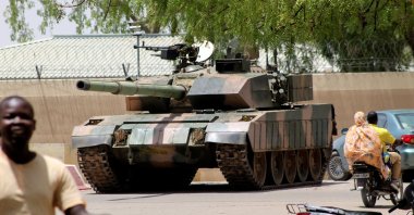 People drive past a Chad army tank near the presidential palace, as fighters from the rebel Front for Change and Concord in Chad (FACT) appeared to be moving toward the capital according to U.S. sources, N'djamena, Chad, April 19, 2021. (Reuters Photo)